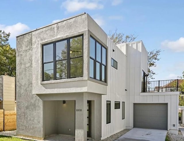 view of property exterior featuring concrete driveway, a balcony, an attached garage, and board and batten siding