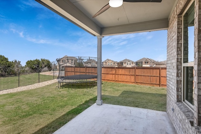 view of yard with a ceiling fan, a patio, a trampoline, a fenced backyard, and a residential view