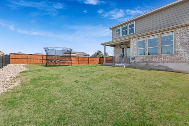 view of yard with a trampoline and a fenced backyard