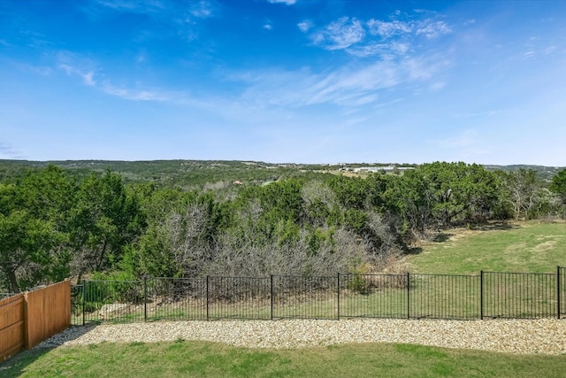 view of yard with a forest view and fence