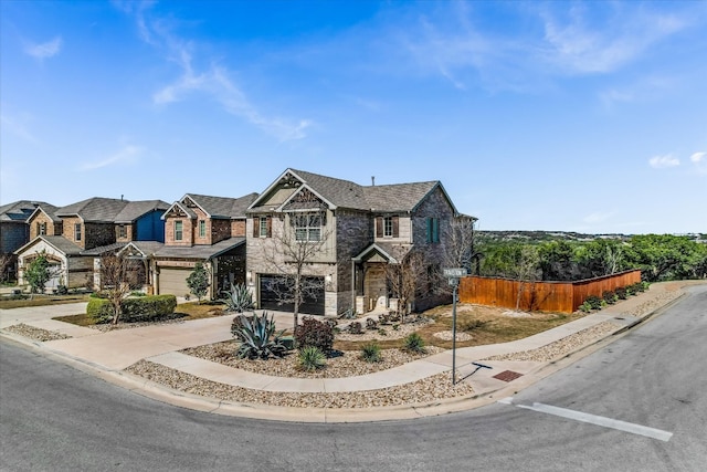 view of front of house with fence, an attached garage, concrete driveway, stone siding, and a residential view