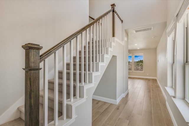 staircase featuring wood finished floors, visible vents, and baseboards