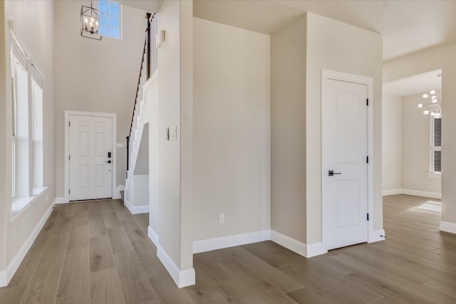 foyer with a notable chandelier, a towering ceiling, baseboards, and wood finished floors