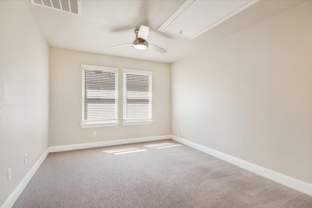 unfurnished room with carpet, baseboards, visible vents, attic access, and ceiling fan