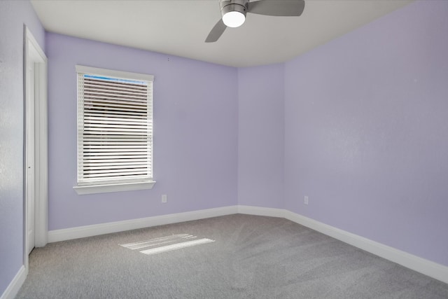 carpeted spare room featuring a ceiling fan and baseboards