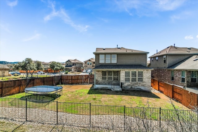 rear view of house with a lawn and a fenced backyard