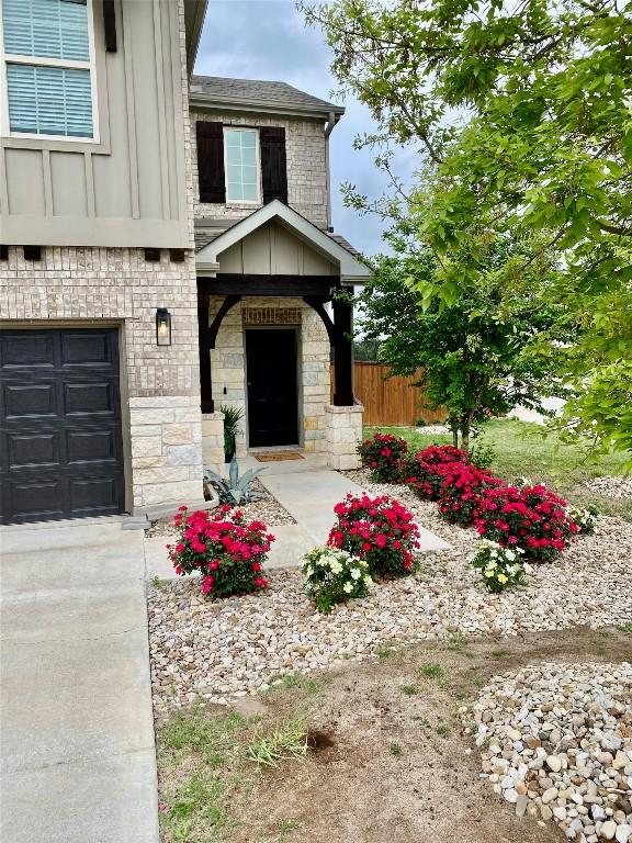 5300 Traviston Dr, Austin, TX 78738 - property entrance featuring an attached garage, board and batten siding, stone siding, roof with shingles, and brick siding