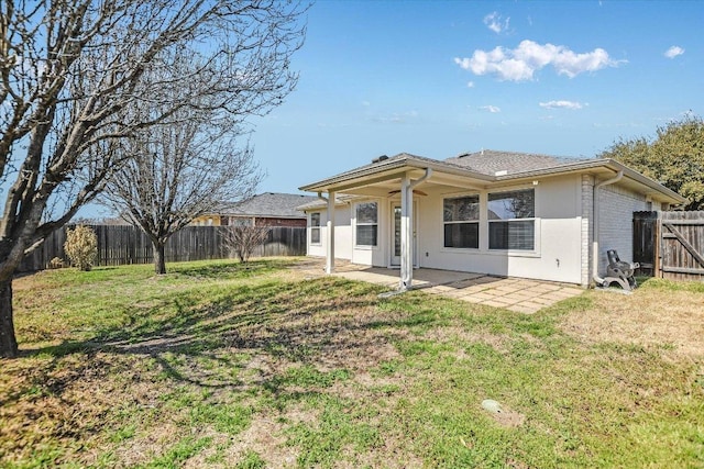 rear view of house with stucco siding, a lawn, a fenced backyard, and a patio area