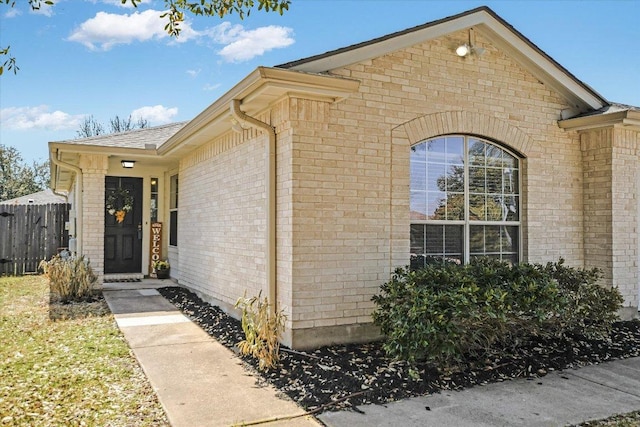 property entrance featuring fence and brick siding