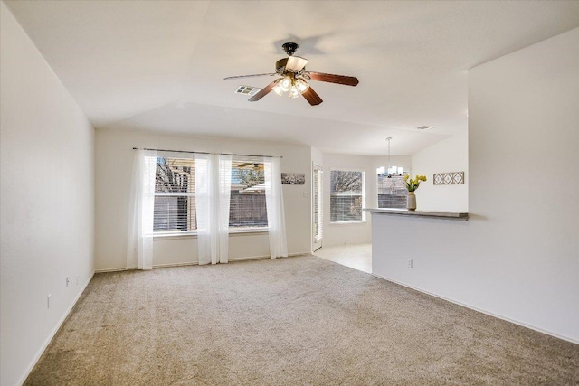 spare room with lofted ceiling, ceiling fan with notable chandelier, visible vents, and light carpet