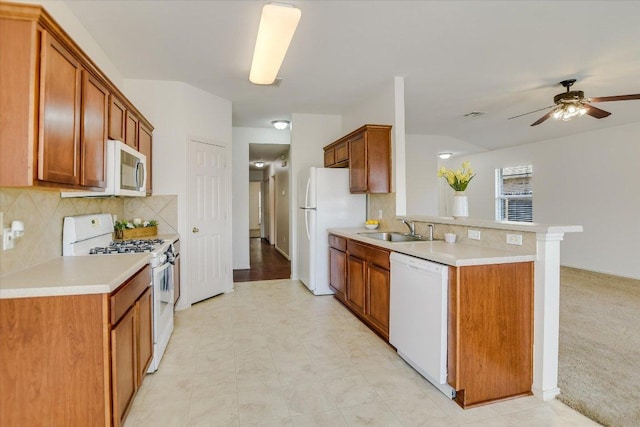 kitchen featuring ceiling fan, light countertops, a peninsula, white appliances, and a sink