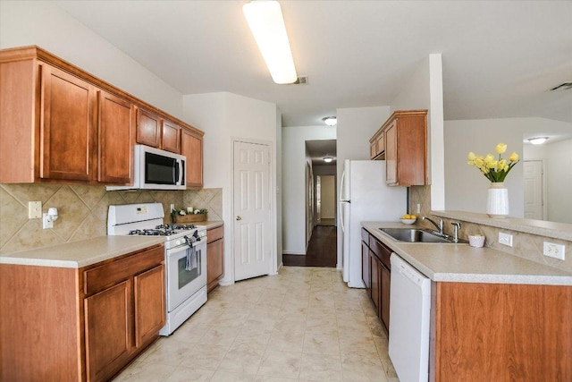 kitchen with white appliances, light countertops, tasteful backsplash, and a sink