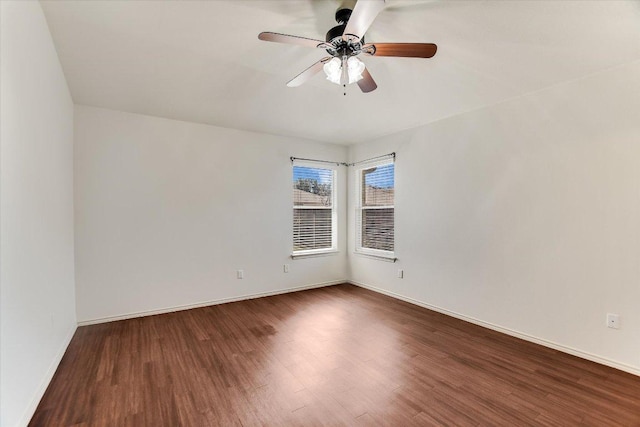 empty room with dark wood finished floors, baseboards, and ceiling fan