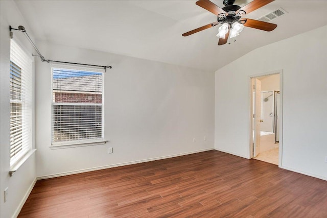 unfurnished room featuring a ceiling fan, wood finished floors, visible vents, baseboards, and vaulted ceiling