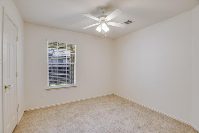 empty room featuring visible vents, light carpet, and ceiling fan