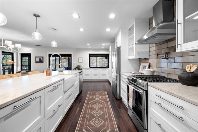 kitchen with stainless steel appliances, dark wood-type flooring, white cabinetry, wall chimney exhaust hood, and backsplash