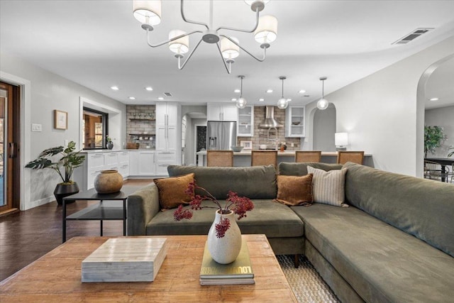 living room featuring visible vents, recessed lighting, wood finished floors, arched walkways, and a notable chandelier