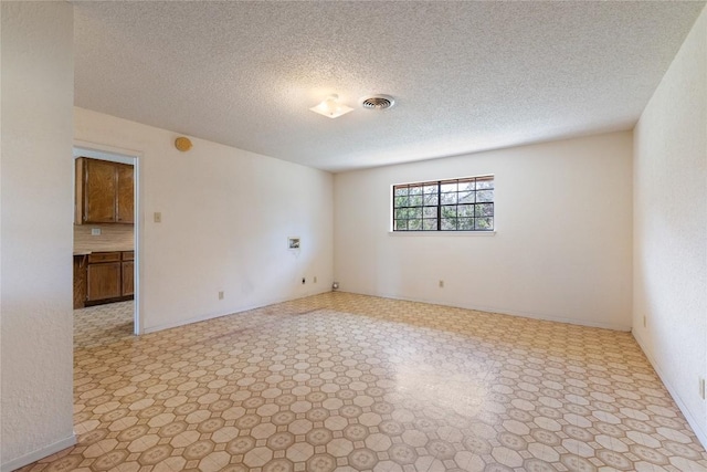 empty room with baseboards, light floors, visible vents, and a textured ceiling