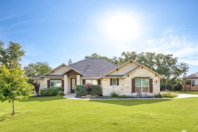 craftsman-style home with stone siding, a chimney, a front lawn, and a shingled roof