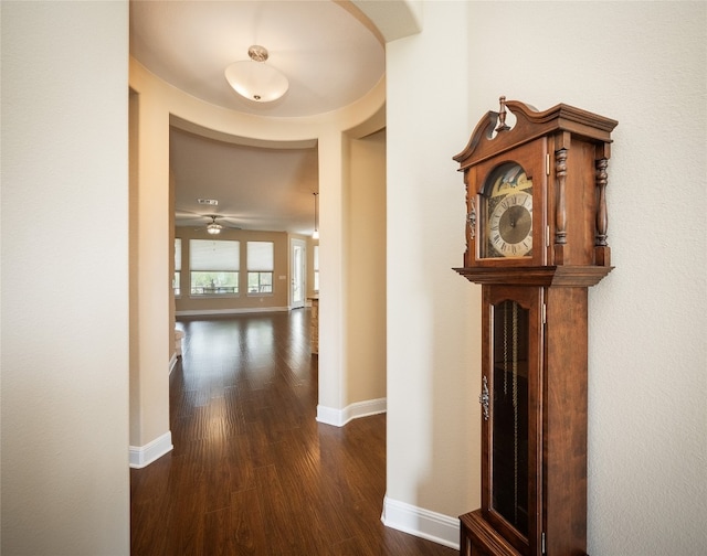 corridor with dark wood-type flooring and baseboards