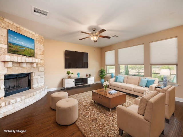 living room with visible vents, a ceiling fan, wood finished floors, and a fireplace