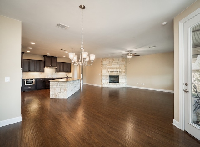 kitchen with visible vents, dark wood finished floors, dark brown cabinets, ceiling fan with notable chandelier, and backsplash