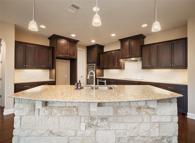 kitchen featuring under cabinet range hood, visible vents, black electric stovetop, and dark brown cabinetry