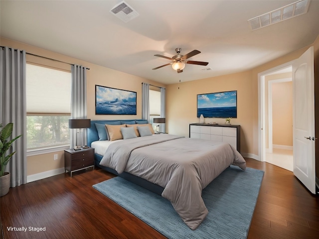 bedroom with a ceiling fan, wood finished floors, visible vents, and baseboards