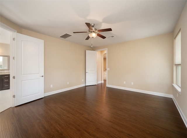 unfurnished room featuring dark wood finished floors, arched walkways, visible vents, and ceiling fan