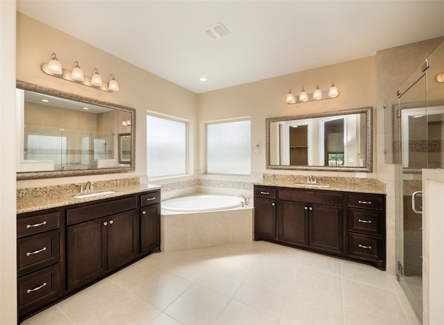 full bath with visible vents, two vanities, a sink, a shower stall, and a bath