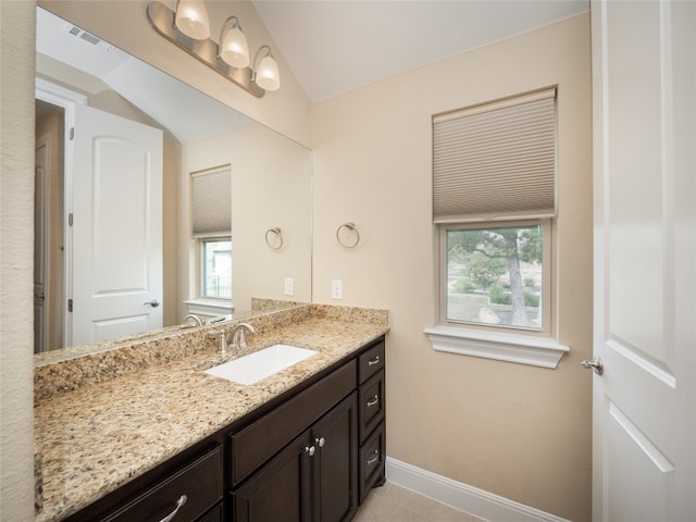 bathroom featuring visible vents, baseboards, vanity, and vaulted ceiling