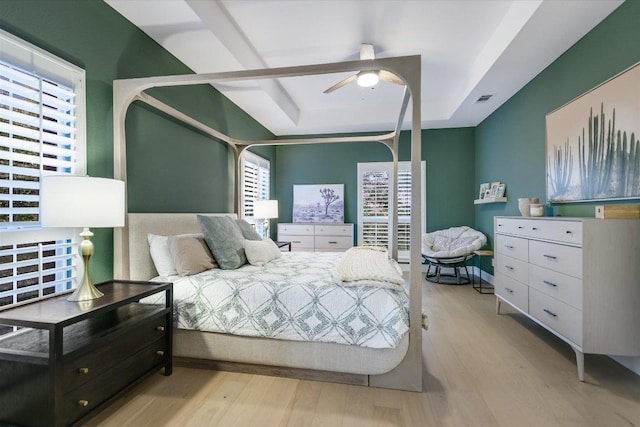 bedroom featuring visible vents, a raised ceiling, wood finished floors, and a ceiling fan