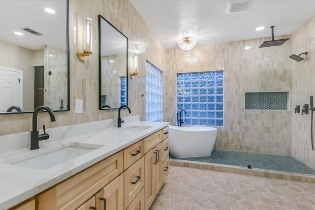 bathroom featuring a sink, visible vents, tile walls, and a tile shower