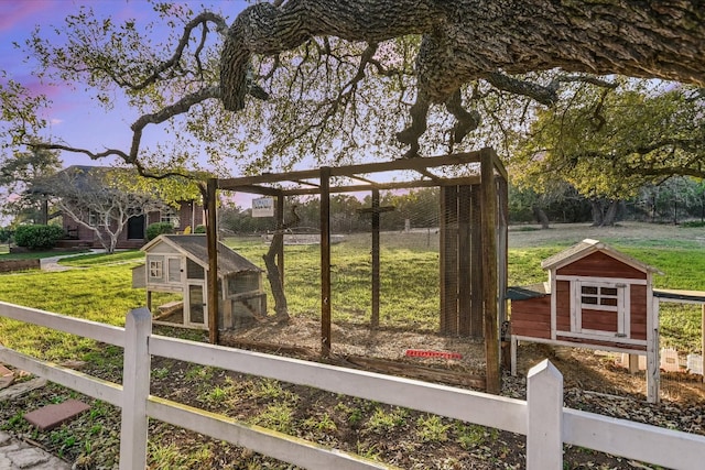 exterior space featuring a lawn, an outdoor structure, exterior structure, and fence