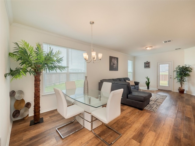 dining area featuring baseboards, visible vents, wood-type flooring, crown molding, and a chandelier