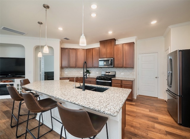 201 Teller Dr, Lockhart, TX 78644 - kitchen featuring stainless steel appliances, a sink, tasteful backsplash, arched walkways, and ornamental molding