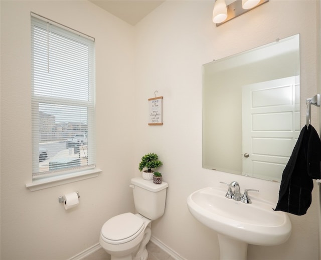 bathroom featuring tile patterned floors, toilet, baseboards, and a sink