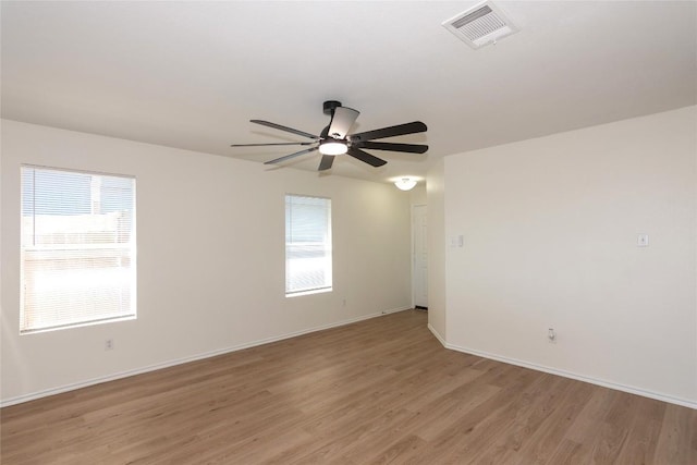 spare room with light wood-type flooring, visible vents, a healthy amount of sunlight, and ceiling fan