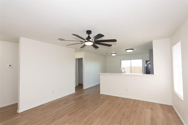 spare room with light wood-style flooring, baseboards, ceiling fan, and a sink