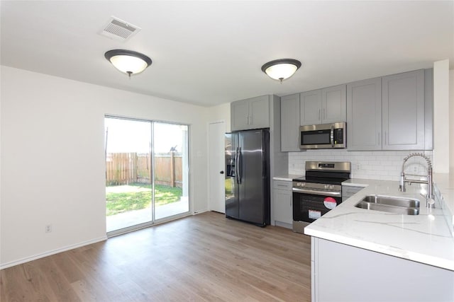 kitchen with a sink, gray cabinetry, visible vents, and stainless steel appliances