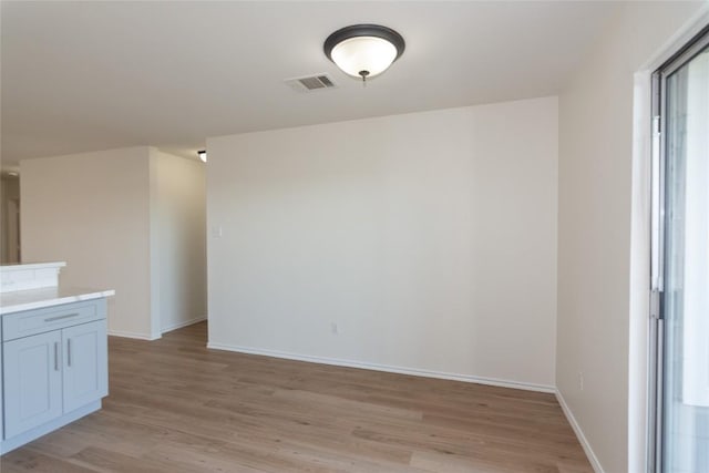 empty room with visible vents, baseboards, and light wood finished floors