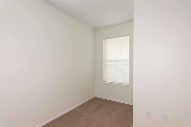 empty room featuring baseboards and dark colored carpet