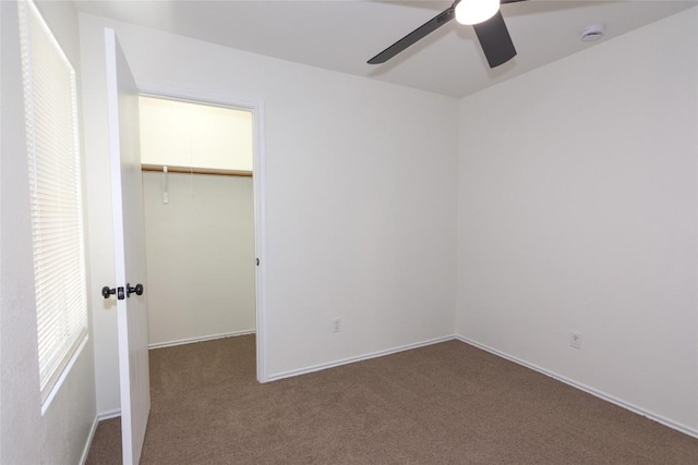 unfurnished bedroom featuring a spacious closet, a ceiling fan, a closet, and carpet floors