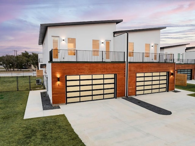 contemporary house featuring stucco siding, fence, concrete driveway, a front yard, and a garage