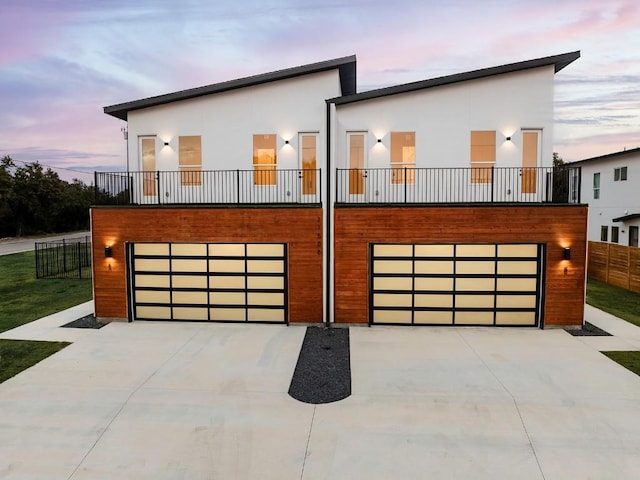 contemporary house featuring a garage, fence, concrete driveway, and stucco siding