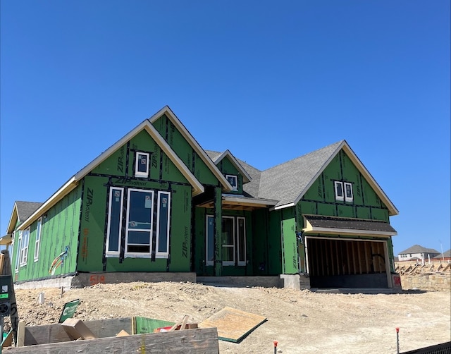 property in mid-construction with a garage, roof with shingles, board and batten siding, and driveway