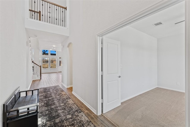 hallway featuring visible vents, wood finished floors, arched walkways, and baseboards