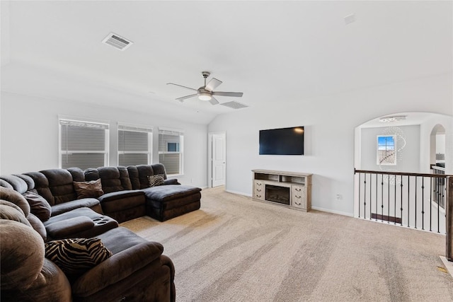 carpeted living area with visible vents, baseboards, ceiling fan, lofted ceiling, and arched walkways