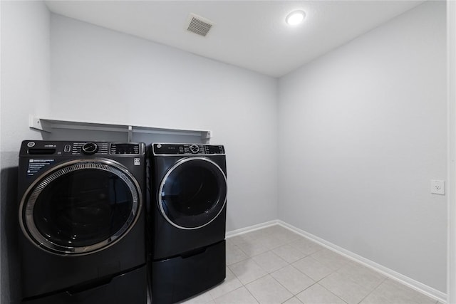 washroom featuring visible vents, washer and dryer, light tile patterned floors, baseboards, and laundry area