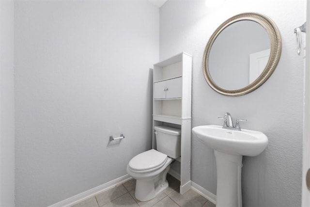 bathroom featuring a sink, baseboards, toilet, and tile patterned flooring